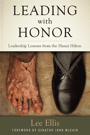 Book cover for "Leading with Honor" by Lee Ellis. The top half shows a bare, scarred foot with a shackle; the bottom, a polished foot in a dress shoe—symbolizing resilience and the leadership lessons valued by CEOs.